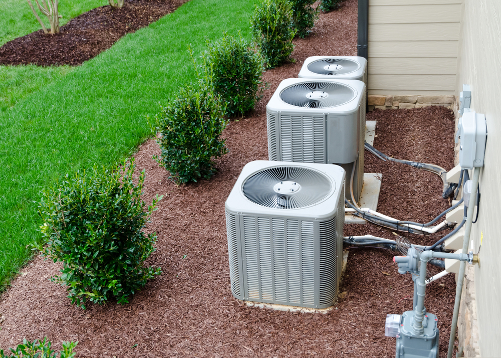 Three air conditioning units outside of a residential building.