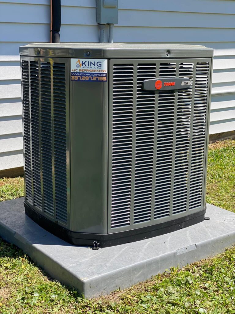 A Trane brand air conditioner unit sitting outside of a residential home.